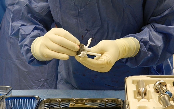 Member of operating theatre team holds Glenius implant and surgical guides 