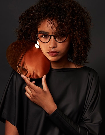 Schwarzes weibliches Modell, das einen Spiegel hält und eine Hoet Cabrio PZ-Brille trägt