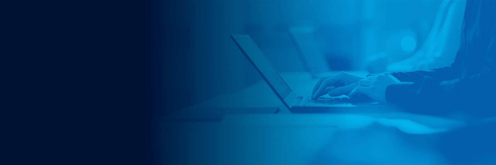 A person typing on a laptop with a blue filter over the image.