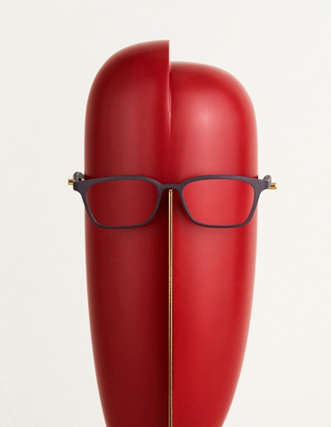 Straight-on, close-up view of black Yuniku Orgreen eyewear on an abstract, red mannequin head