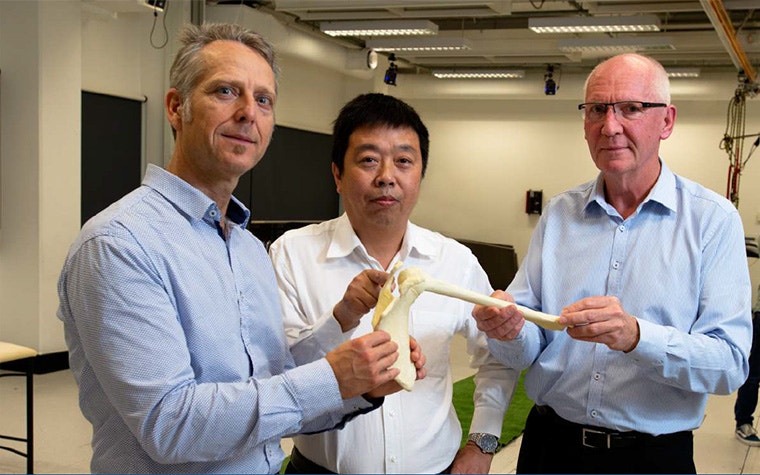 Three Joint Biomechanics team members holding up a shoulder model