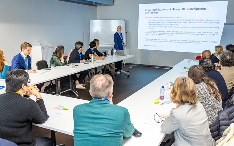 A woman standing in front of a screen presenting to a group of attendees at the Leading Minds Summit