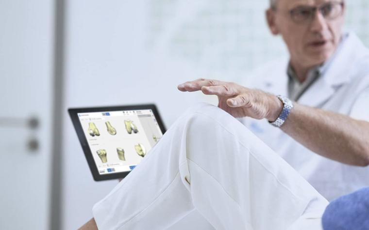 Doctor showing digital images of anatomy on a screen while talking to a patient laying down