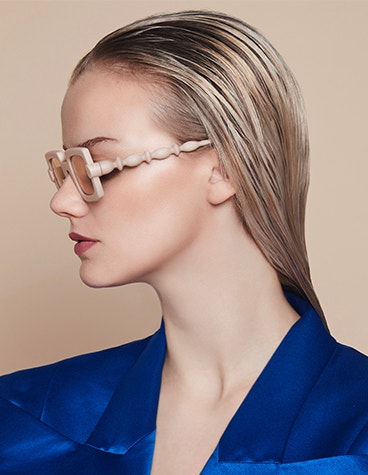 Modèle féminin aux cheveux gominés regardant sur le côté, portant des lunettes BAARS x Gogosha de couleur nude.