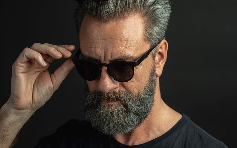 Male model holding Morrow Optics sunglasses on his face while looking downward