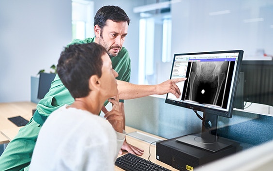 Man wearing scrubs is pointing to a computer screen with the OrthoView software next to a woman