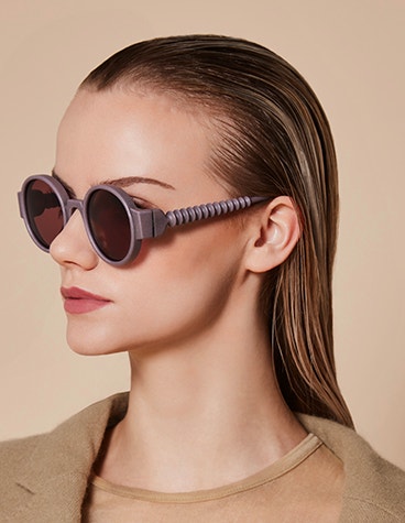 Schräge Nahaufnahme eines weiblichen Modells, das eine lila Sonnenbrille mit schraubenartiger Struktur aus der Kollektion BAARS x GOGOSHA trägt