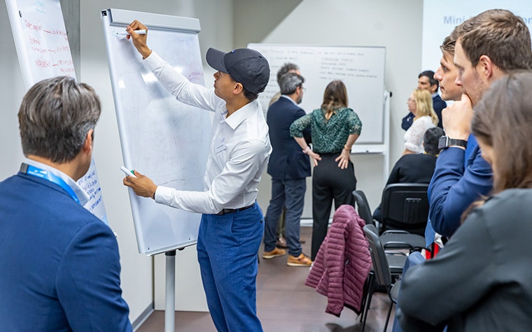 A Materialise team member writing on a whiteboard with a group of Leading Minds attendees