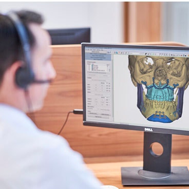 Mann mit Headset vor einem Computer, der ein 3D-Modell eines Schädels zeigt