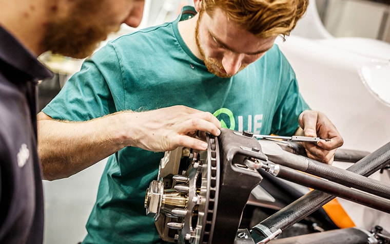 El ingeniero de InMotion ajusta la conexión de la horquilla de metal impresa en 3D del auto de carreras