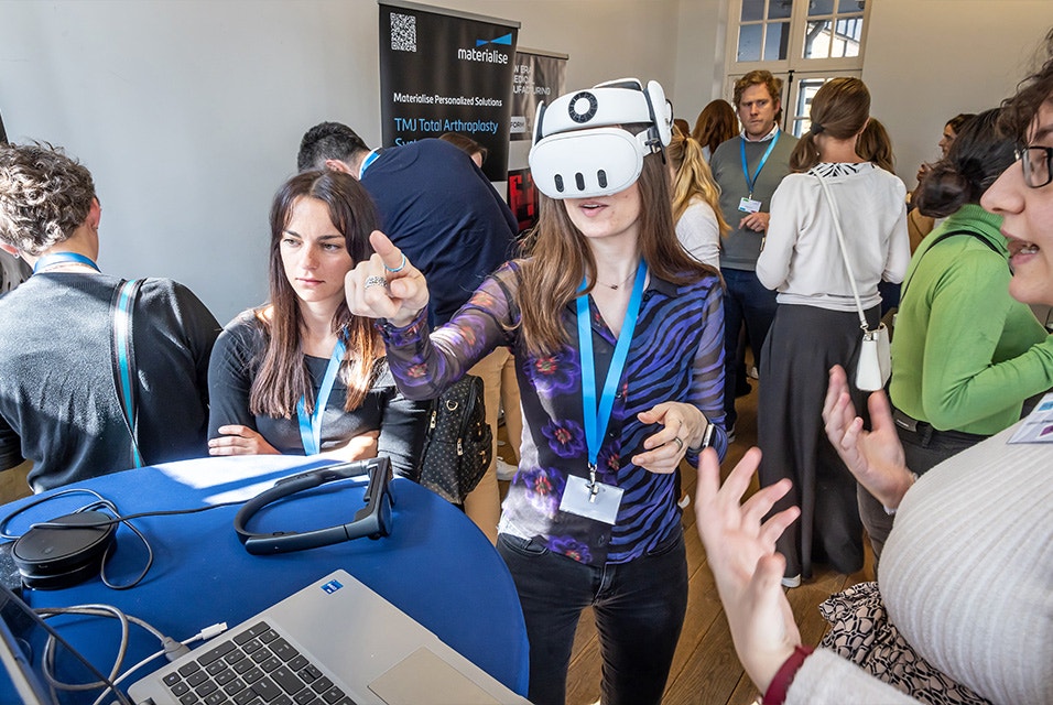 Three women standing around a table, with one woman wearing augmented reality goggles, at Materialise's 3D Planning and Printing in Hospitals Forum (2025).