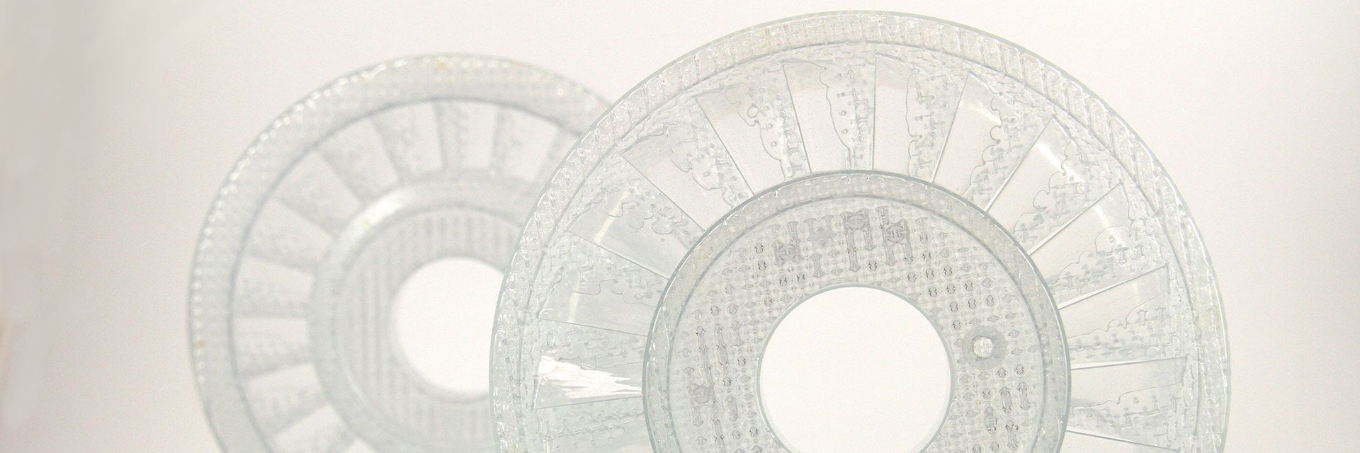 Two transparent, disc-shaped plastic molds in front of a white background