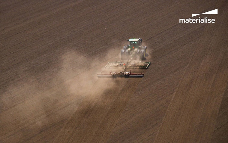 A farm machine crosses a dusty field