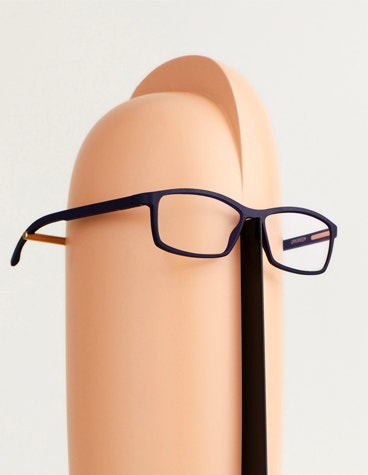Stab, mit dem eine schwarze Yuniku+Ørgreen-Brille an einem abstrakten Schaufensterpuppenkopf aufhängt wird