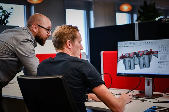 Two men look at the design of a drone on a computer screen