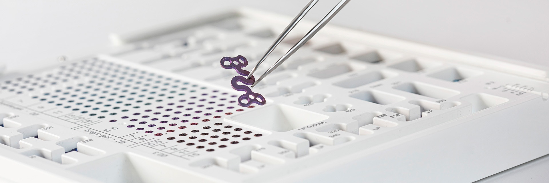 Tweezers pulling the S-plate out of the Orthognathics module, including various screws