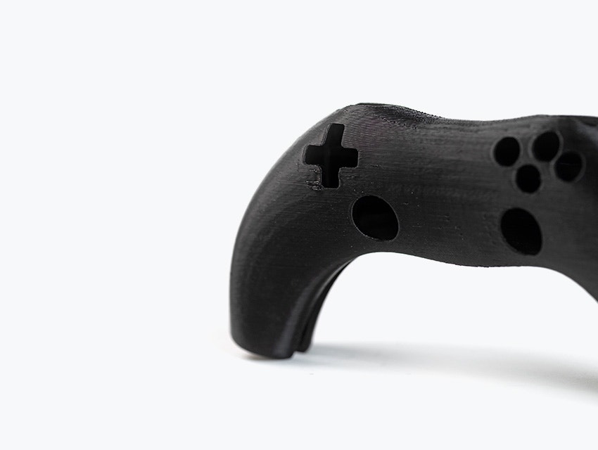 Un controlador de videojuego impreso en 3D en color negro, impreso en ABS-ESD7 mediante modelado por deposición fundida.