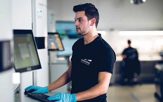 Materialise production team members looking at a screen on a 3D printer