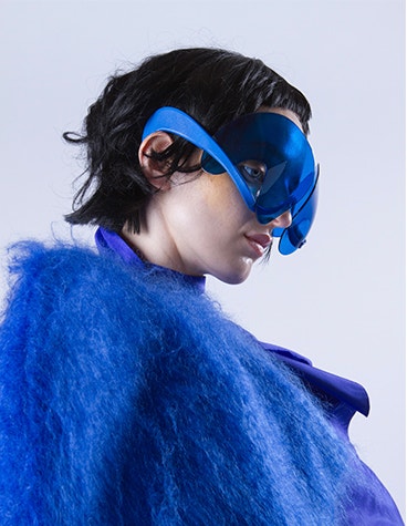Model wearing a blue furry jacket and blue, artistic sunglasses designed by David Ring