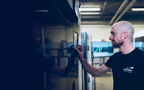 Materialise employee in a production area, operating the control panel of a 3D printer