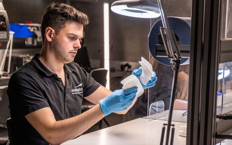 Materialise employee inspecting two 3D-printed insoles in a production environment