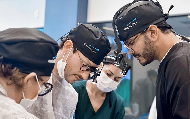 Medical professionals wearing magnifying loupes and surgical caps during a Materialise CMF Wet Lab training session.