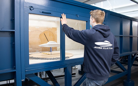 Man from the AGORIA solar team looking at a 3D-printed design of a solar car inside a wide tunnel