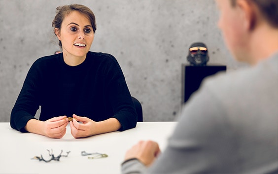 Materialise employee in a meeting room with 3D-printed eyewear, speaking to a colleague across the table