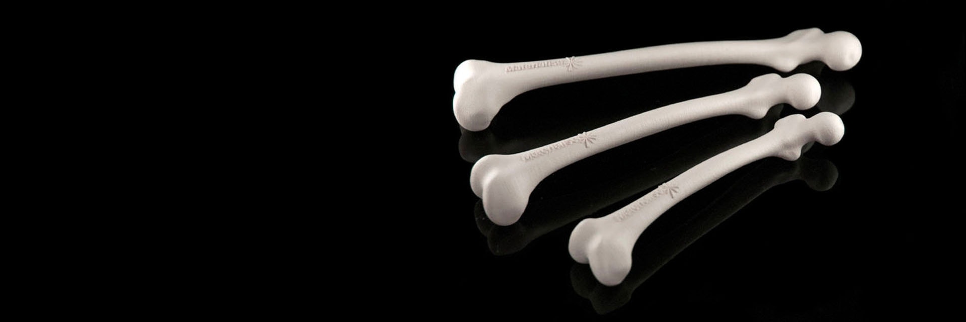 Three 3D-printed bone models with the Materialise logo on them