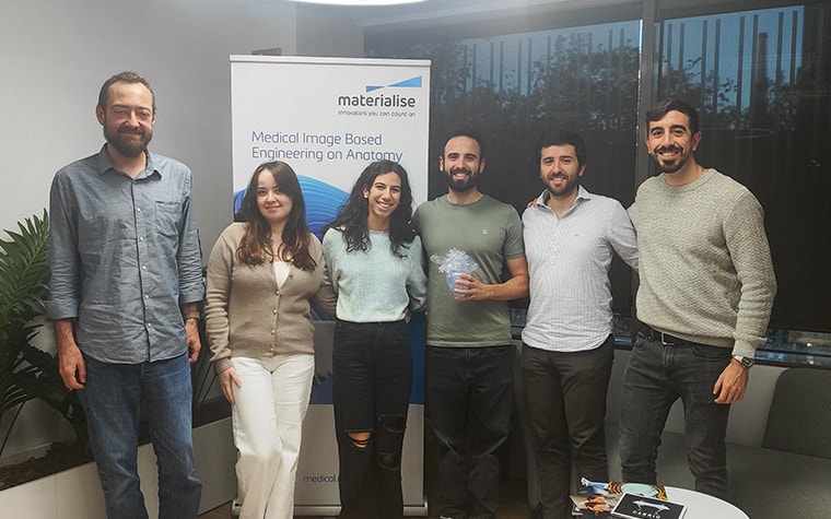 Four men and two women standing in front of a roll-up banner with the text "Medical Image Based Engineering on Anatomy"