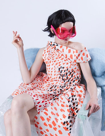 Model sitting in a chair wearing pink sunglasses designed by David Ring