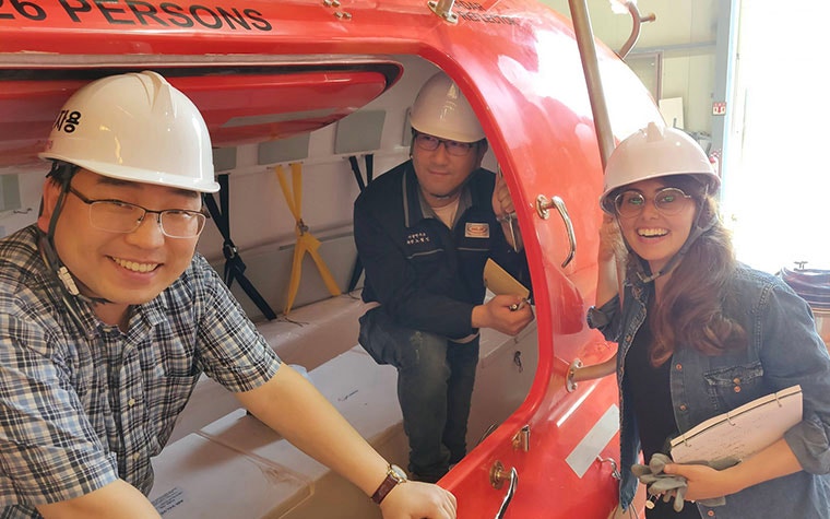 Mindware and Hyundai team members smiling and posing near a lifeboat