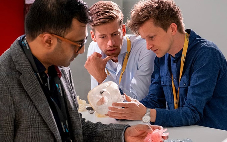 3 men examine 3D-printed anatomical models 