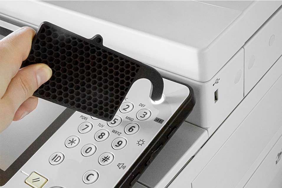 Person pressing a button on a printer using a 3D-printed badge holder with a hooked corner