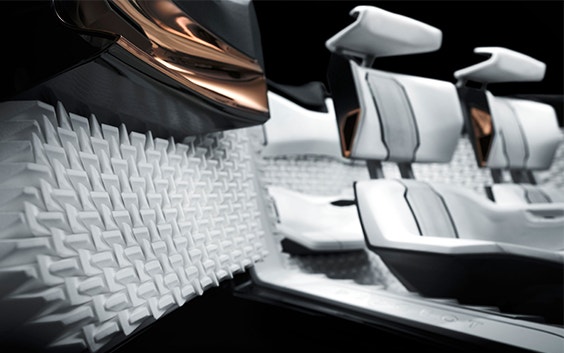Des sièges de voiture blancs et gris imprimés en 3D avec des accents de bronze brillant dans chaque accoudoir.