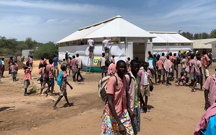 Groups of people walking around outside of a Maggie Shelter