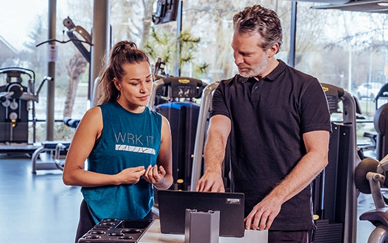 Physical therapist and a patient looking at a monitor in an exercise room