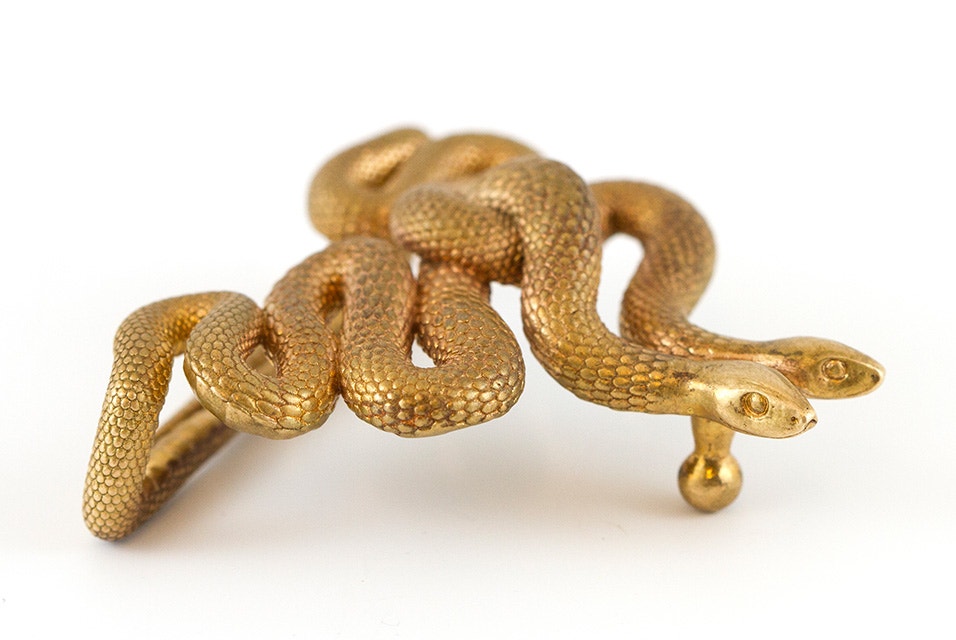 Una hebilla de cinturón de oro con forma de dos serpientes entrelazadas, realizada mediante fundición a la cera perdida.