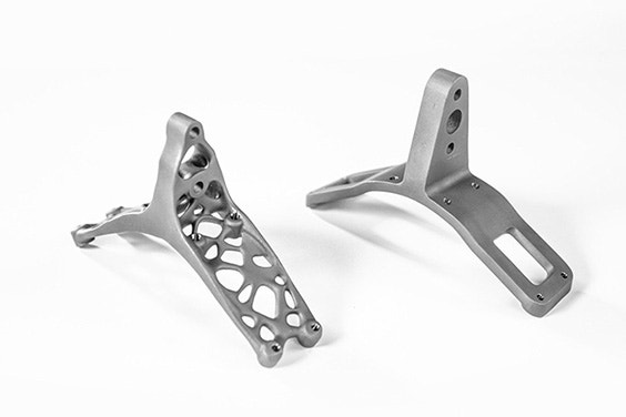 Two titanium brackets side by side. The lightweight bracket called ENDY on the left is based on a generative design and has irregular holes