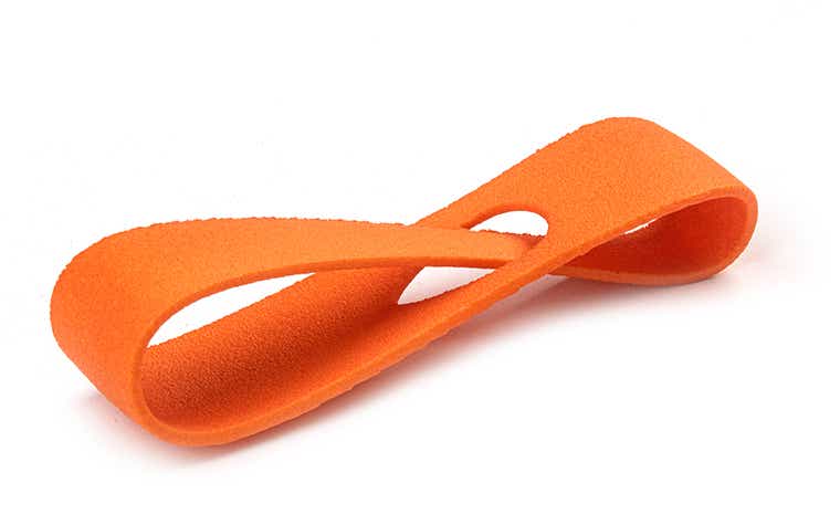 Eine orangefarbene 3D-gedruckte Schlaufe aus PA 12, die im Lasersinterverfahren hergestellt und farbig eingefärbt wurde.