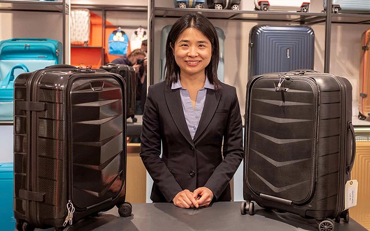 Vivien Cheng, Head of Product Development bei Samsonite Europe, steht neben einigen Samsonite-Koffern