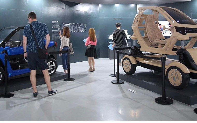 People in a showroom looking at car designs