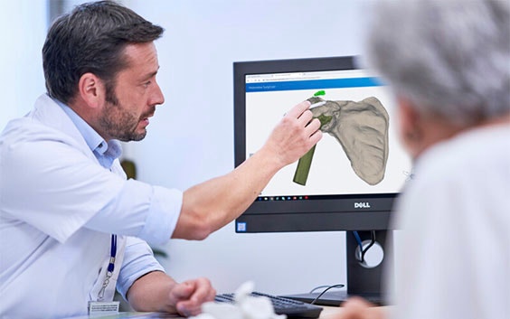 Man pointing to a digital image of a hip next to a patient