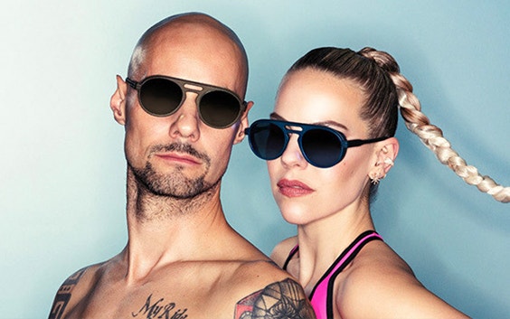 A topless male model and female model in athletic wear posing while wearing 3D-printed sunglasses from Odette Lunettes