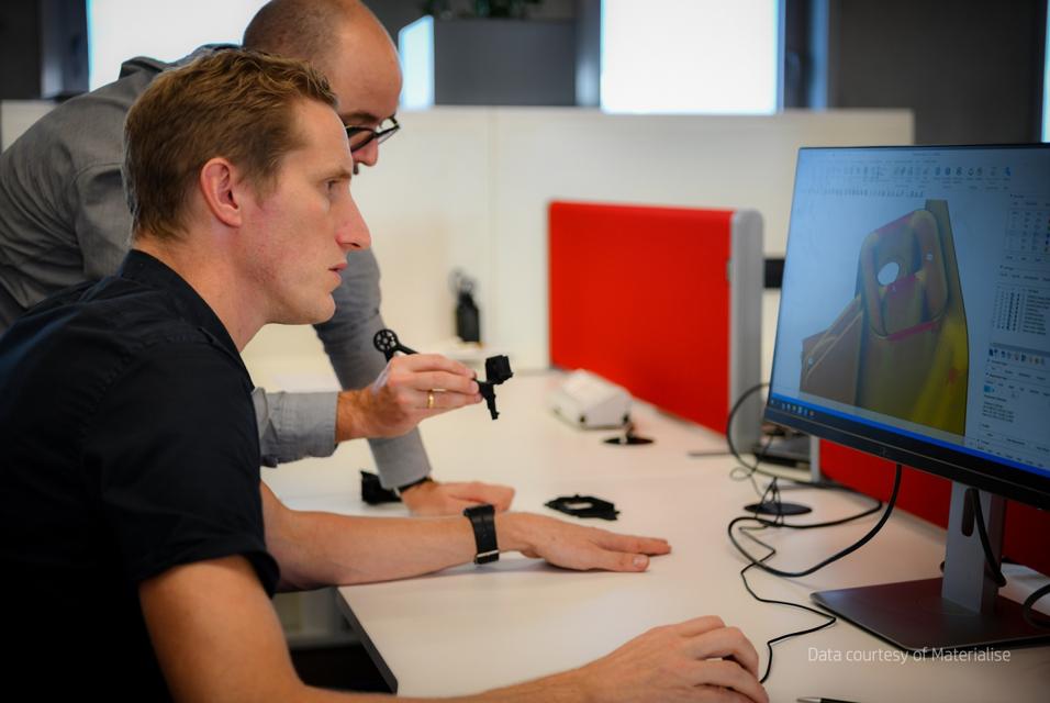 Two people reviewing a 3D design on a computer screen