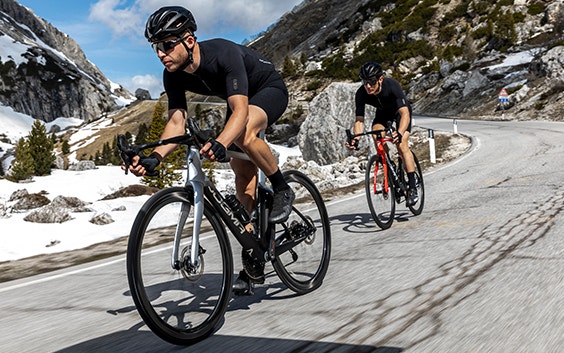 Two cyclists riding Pinarello’s new racing bike on a mountain road  