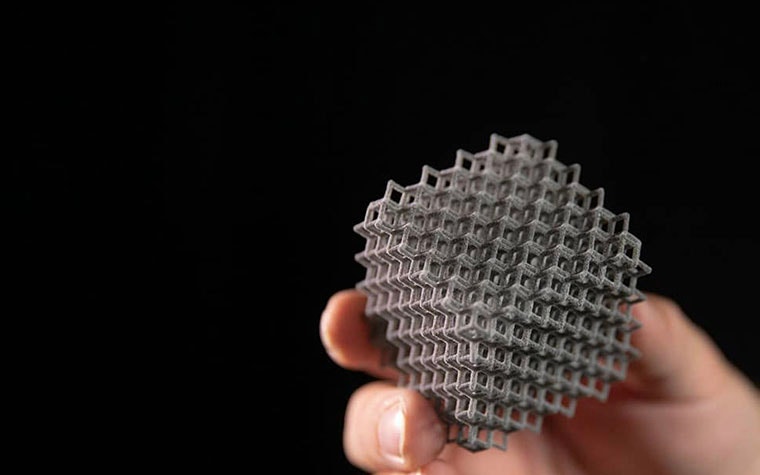 A person holding a 3D-printed part with a lattice design