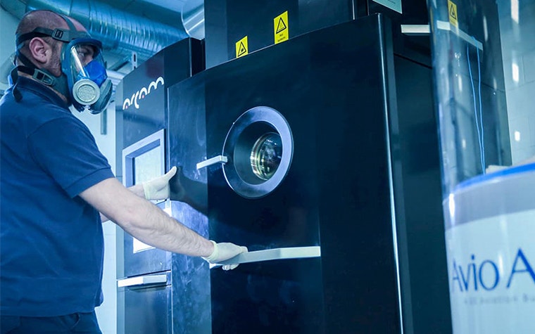 Man in a safety mask opening an Arcam EBM machine 