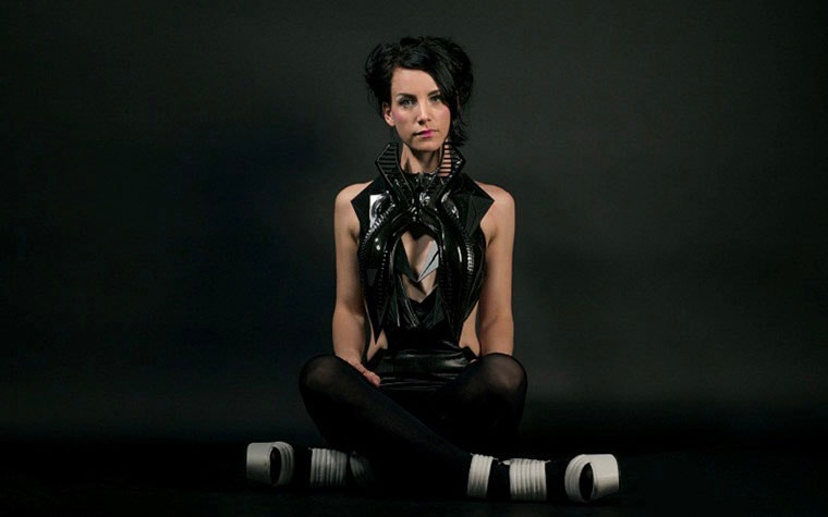 Model sitting cross legged, wearing a 3D-printed outfit