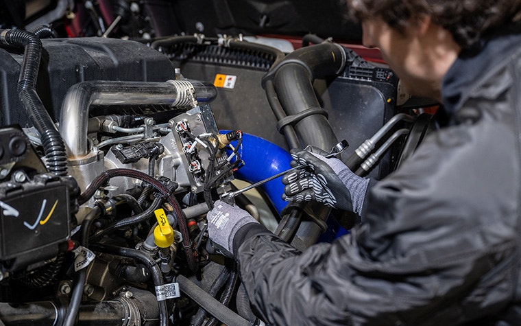 An engineer installs CMB.TECH's dual-fuel hydrogen combustion system into a truck.